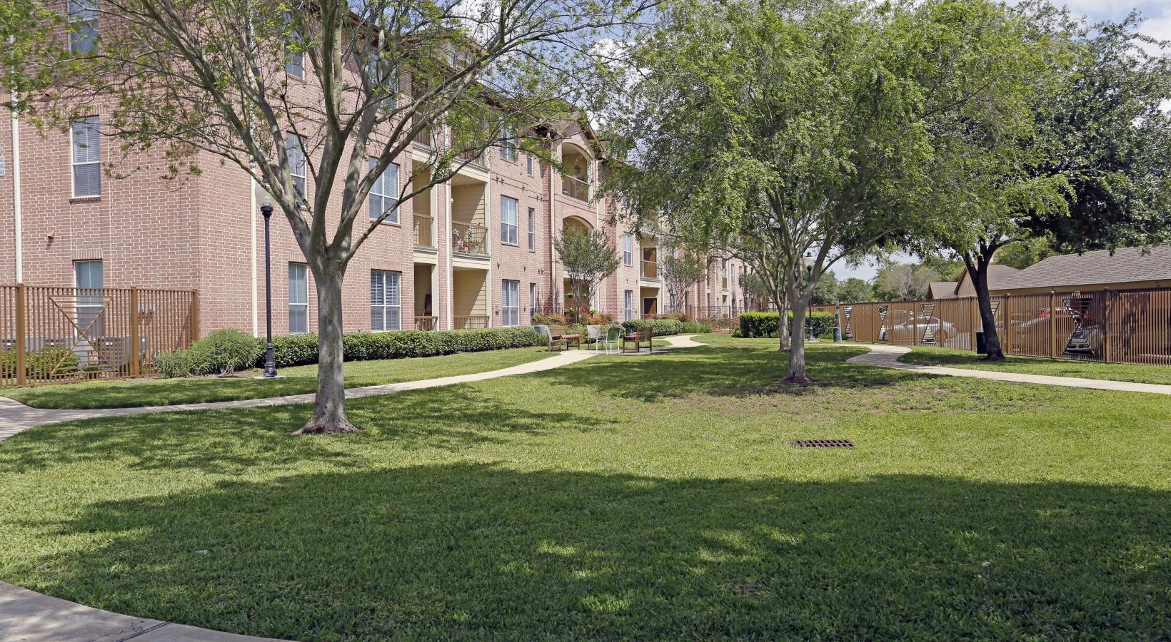 The essence of exceptional living a large brick building with trees and grass in front of it