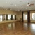 a large room with a wood floor and a wall of mirrors and windows