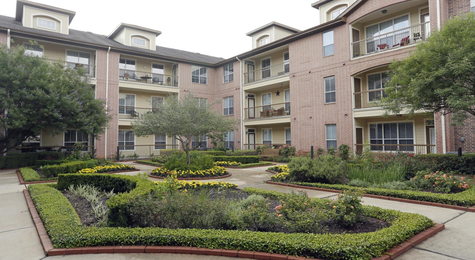 Settle into comfort at Elate Royal Oaks a courtyard with trees and plants in front of a building