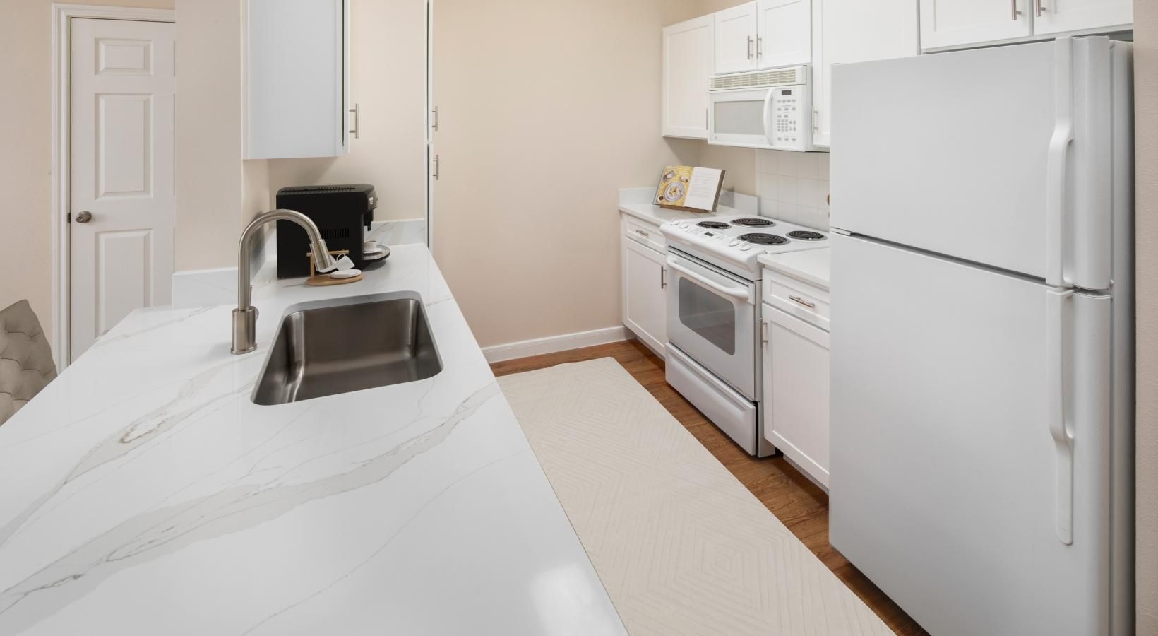 Spacious kitchens with thoughtful details a kitchen with white cabinets a sink a fridge a stovetop
