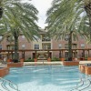 a swimming pool in front of a building with palm trees