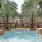 a swimming pool in front of a building with palm trees